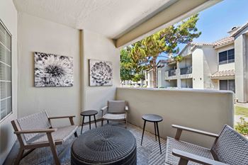 a balcony with a table and chairs and a tree in the background